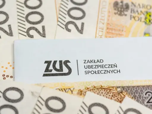 Logo ZUS na tle polskich banknotów 200 zł.